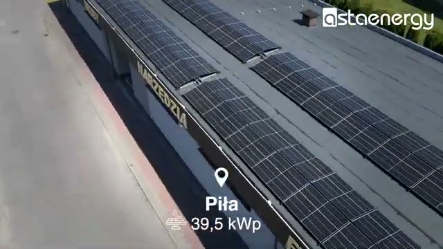 Moduły fotowoltaiczne na dachu obiektu w Pile – szeroki widok z drona.